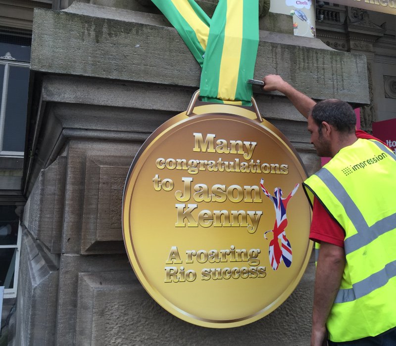 Impression’s deliver team installing external ‘congratulations’ foamex graphic for Bolton Museum