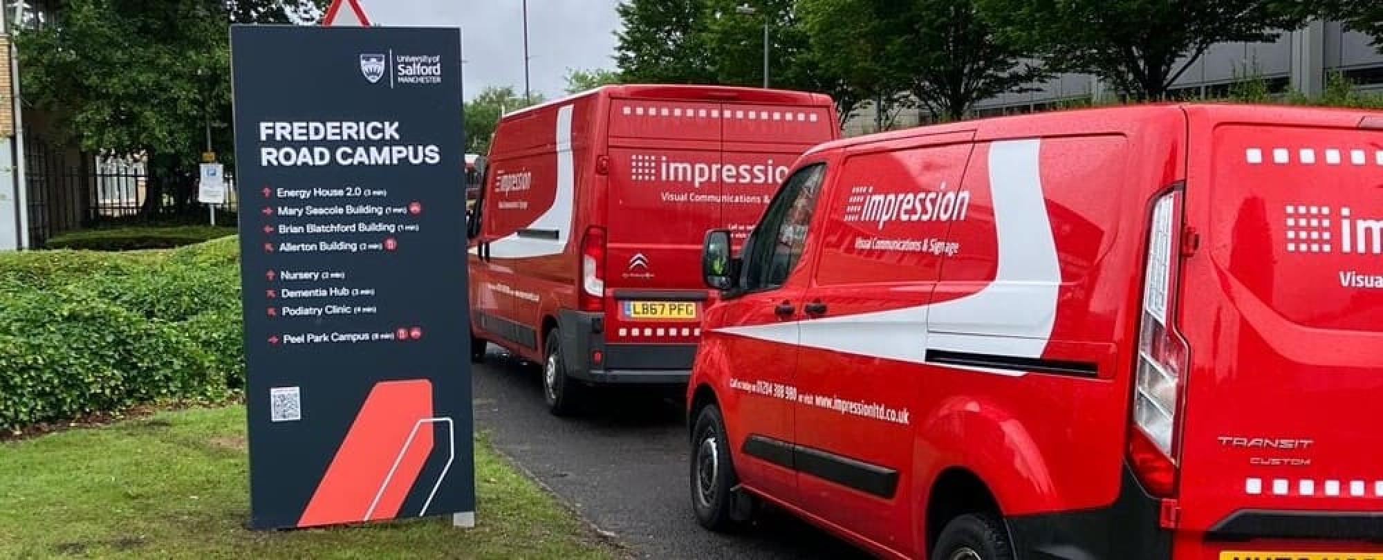 Impression branded red vans next to a newly installed branded wayfinding sign for the University of Salford