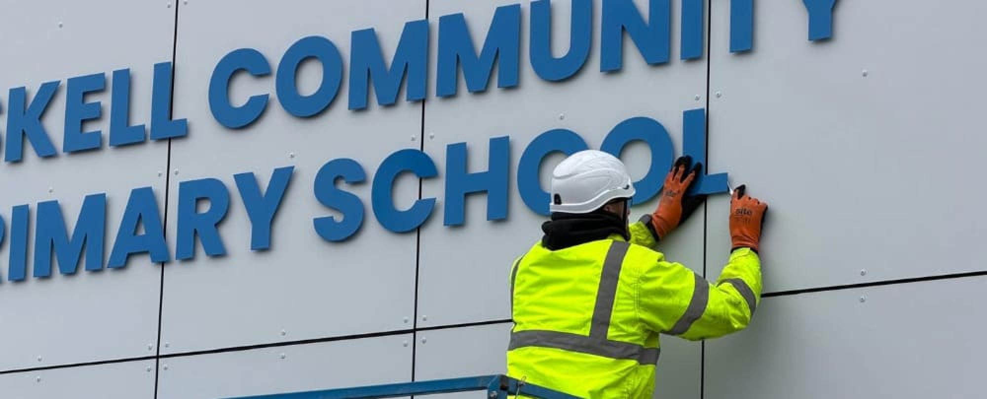Impression's Deliver team installing letter signage on the exterior wall of Gaskell Community Primary School in Bolton