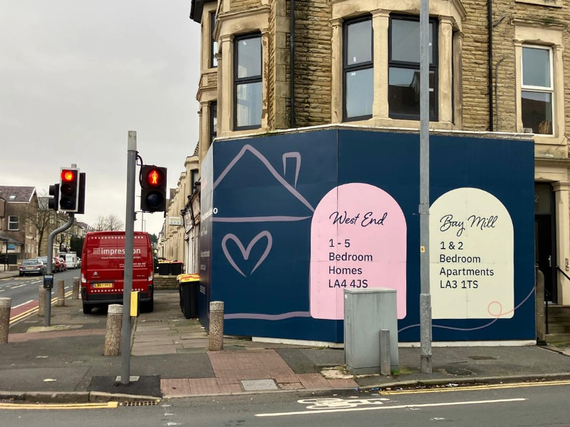 Construction hoarding attached to flats on the corner of a street in Morecambe, advertising two rental opportunities by developer PlaceFirst.