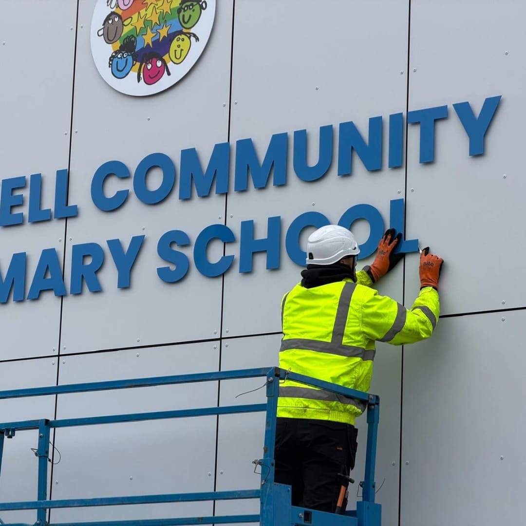 Impressions Deliver team installing letter signage on the exterior wall of Gaskell Community Primary School