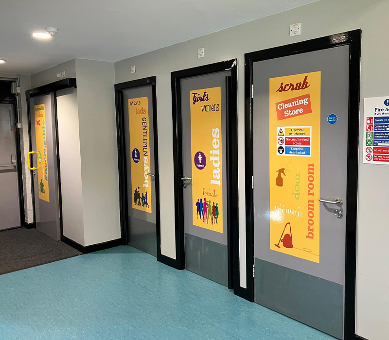 Four doors inside the Young Peoples Centres leaving into toilets and a cleaning store room, with door vinyl that has the Young peoples Centres yellow branding on, installed by Impression
